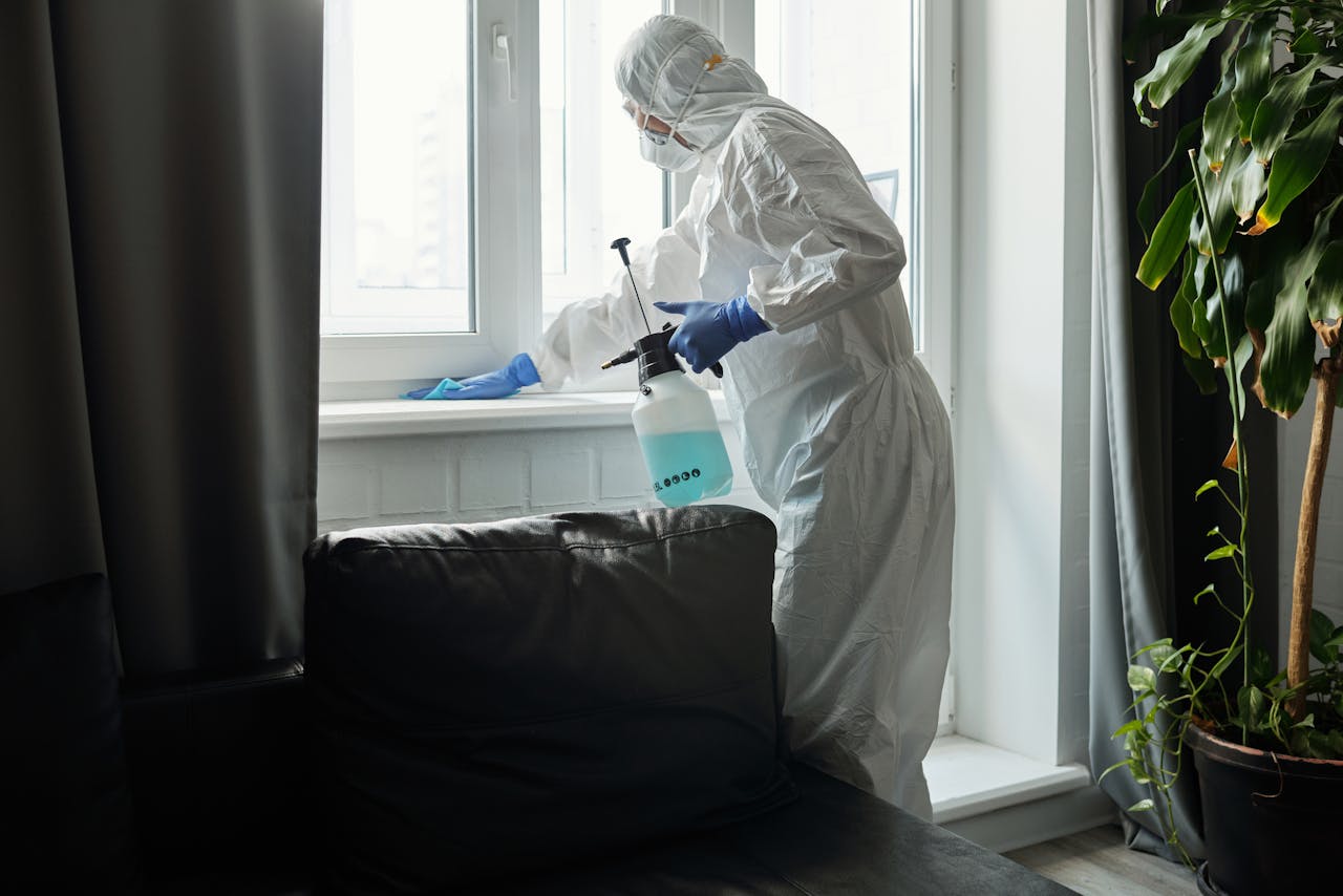 services-bg Person in PPE disinfecting indoor window area during COVID-19 pandemic.